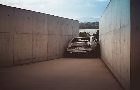 Photograph of a crashed car between two walls